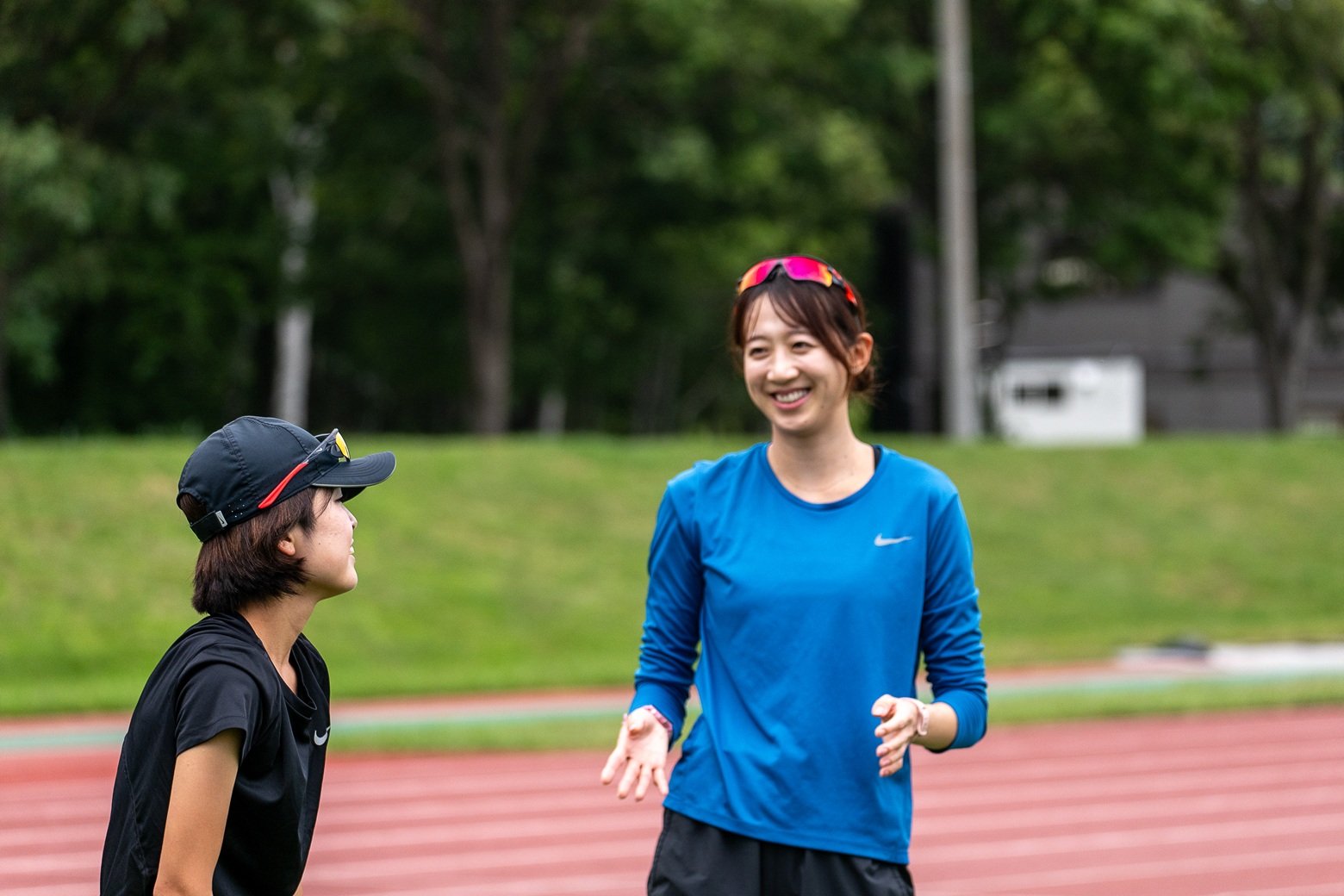 陸上競技場で小坂井 智絵（こさかい ちか）選手と談笑する牛 佳慧（ぎゅう かえ）選手（写真右）